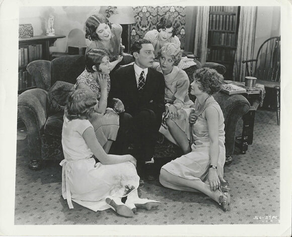 BUSTER KEATON SURROUNDED BY FLAPPERS IN THE CAMERAMAN (1928)